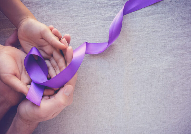 Hands holding Purple ribbons, toning copy space background, Alzheimer disease, Pancreatic cancer, Epilepsy awareness, domestic violence wareness